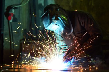 Fabrikada çalışan kaynakçılar metal üretiyorlar.