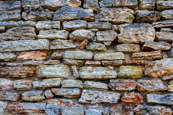 Eine alte Mauer aus Stein. Altes Mauerwerk. Der Stein ist in der Wand. Steinzaun. — Stockfoto