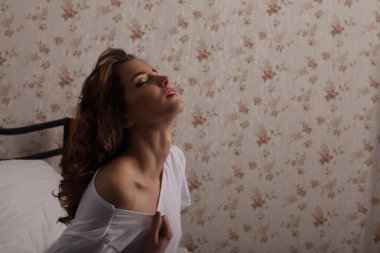 Uzun ince bacakları yatak poz ile gülümseyen güzel esmer kadın