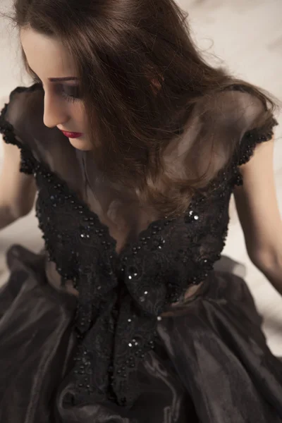 Portrait of beautiful young brunette woman princess in black dress lying down on floor — Stock Photo, Image