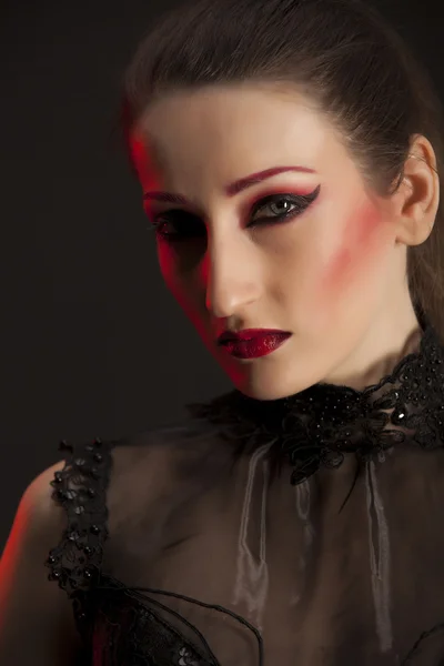 Retrato de una hermosa joven morena en vestido negro sobre fondo oscuro, resaltado con rojo. Retrato de primer plano —  Fotos de Stock