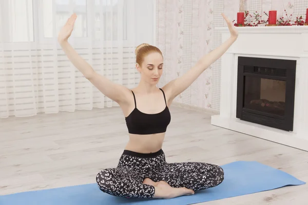 Красивая молодая женщина практикует йогу дома на коврике - медитация — стоковое фото