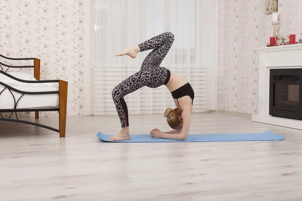 Vacker ung kvinna utövar yoga, utför full bridge hemma, sidovy — Stockfoto
