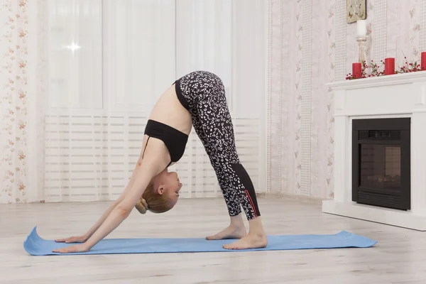 Hermosa joven practicando yoga estirándose en casa. Posada de perro — Foto de Stock