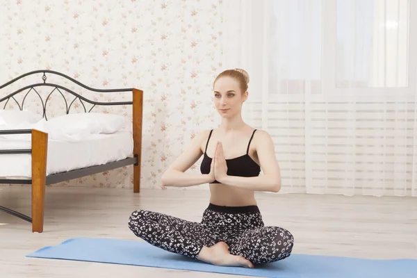 Hermosa joven practicando yoga en casa sobre alfombra - meditación —  Fotos de Stock