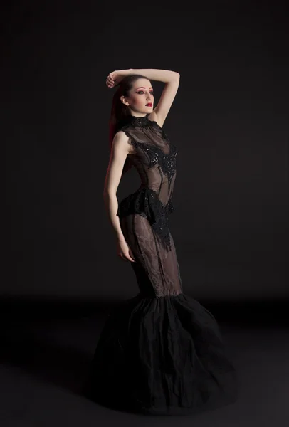 Karanlık bir arka plana dayanır kırmızı ile vurgulanacaktır, siyah elbiseli güzel genç esmer kadın portresi — Stok fotoğraf