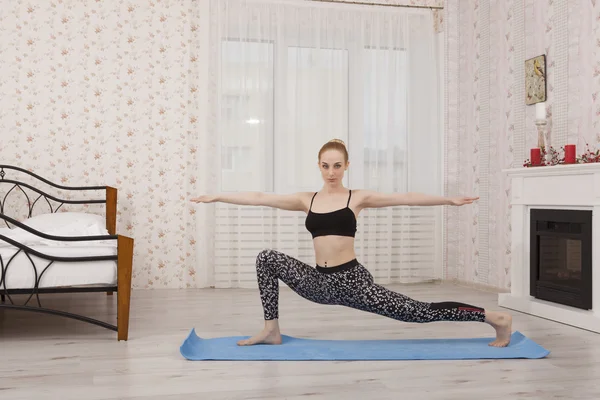 Hermosa joven practicando yoga estirándose en la estera, pose guerrera —  Fotos de Stock