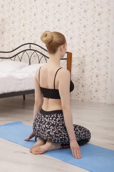 Hermosa joven practicando yoga estirándose en casa sobre una esterilla —  Fotos de Stock