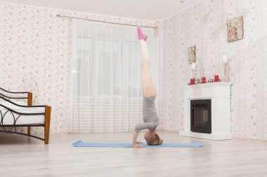 Güzel sarışın kadın evde mavi mat gri gömlek, pembe çoraplı ile germe yoga uygulamak. Kollar ve eller üzerinde durmak