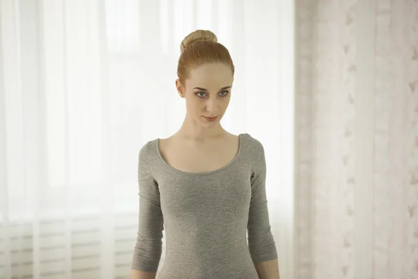 Hermosa mujer rubia practicando yoga estirándose en casa en body gris y calcetines rosados — Foto de Stock