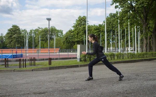 Giovane donna felice che si estende e si riscalda prima di treno all'aperto sullo stadio. Runner ragazza, campo sportivo — Foto Stock