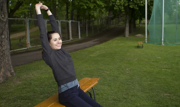 Giovane donna felice che si estende e si riscalda prima di treno all'aperto sullo stadio. Runner ragazza, campo sportivo — Foto Stock