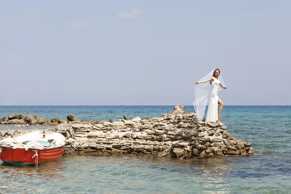 美しい花嫁は華やかな白いウェディング ドレスで海の上の崖上に立つ — ストック写真