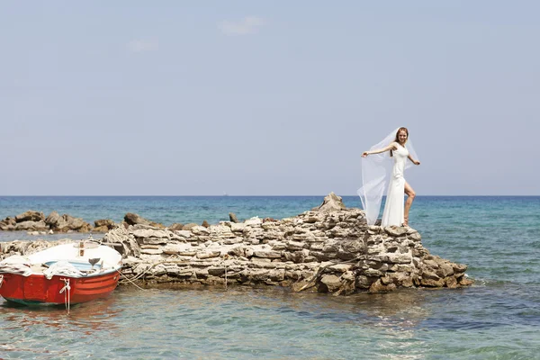 Beautiful bride stands on a cliff above the sea in glamorous white wedding dress — Stock Photo, Image