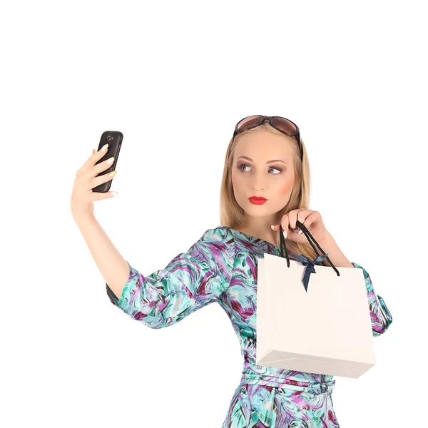 Hermosa chica sosteniendo bolsas de compras y tomando selfie con teléfono celular aislado —  Fotos de Stock