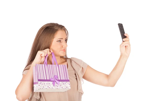 Belle fille tenant des sacs à provisions et prenant selfie avec téléphone cellulaire isolé — Photo