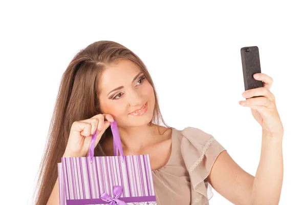 Hermosa chica sosteniendo bolsas de compras y tomando selfie con teléfono celular aislado —  Fotos de Stock