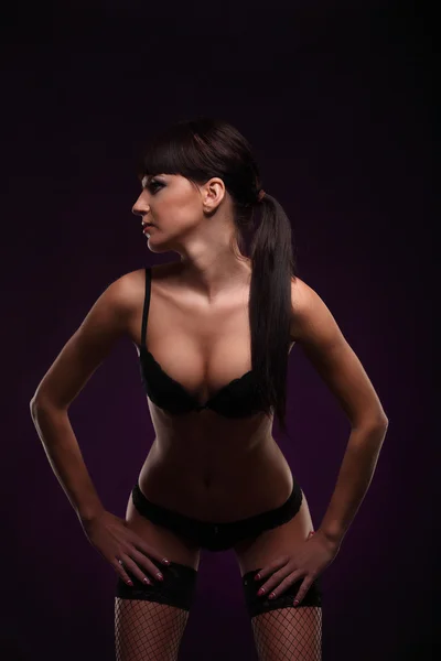Schöne junge Frau in Dessous Körper posiert über dunkelblauem Hintergrund — Stockfoto