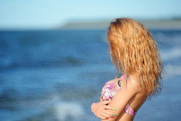 Portret van gelukkig sexy meisje in roze bikini poseren tegen zee — Stockfoto