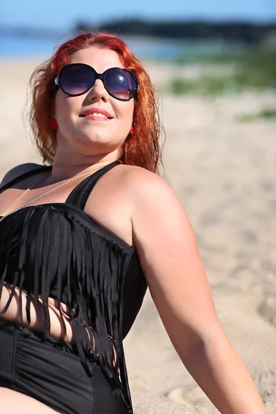 Γυναίκα κοκκινομάλλα σε γυαλιά ηλίου που αναπαύεται στην παραλία — Φωτογραφία Αρχείου