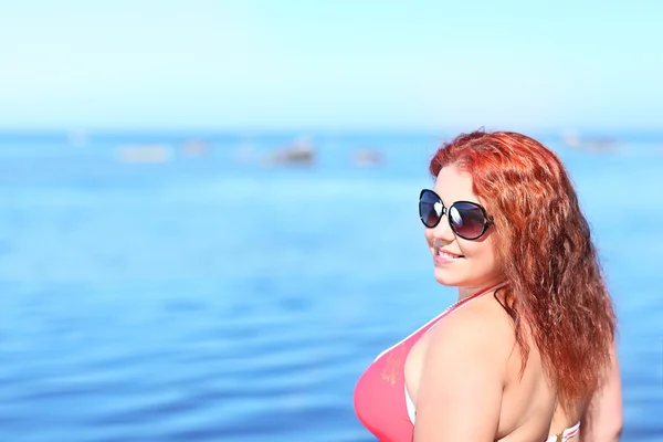 Rossa donna in occhiali da sole a riposo sulla spiaggia — Foto Stock