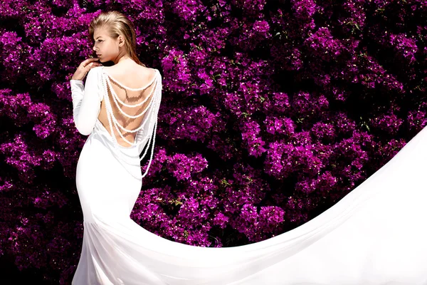 Elegante ragazza in abito bianco sopra i fiori . — Foto Stock