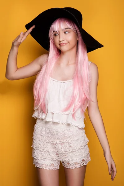 Young girl in pink hair posing on yellow background. — Stock Photo, Image