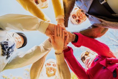 Bir grup arkadaş ellerini birleştiriyor, farklı yaşlardan insanların arkadaşlığı konsepti. Fotoğraf aşağıdan..