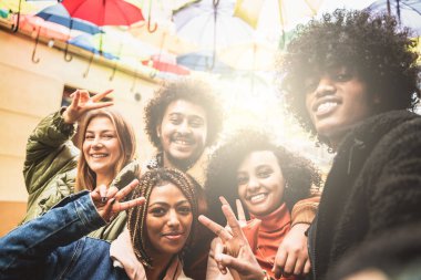 Bir grup çok ırklı arkadaş birlikte eğleniyor, sosyal medya için selfie çekiyor. Kameraya gülümseyen melez kızlar ve oğlanlar. Gençlerin yaşam tarzı konsepti.