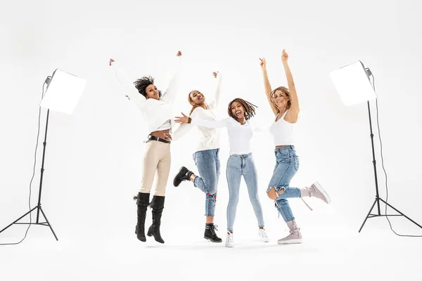 Vier Tausendjährige Multiethnische Freundinnen Springen Und Lachen Auf Weißem Studiohintergrund — Stockfoto