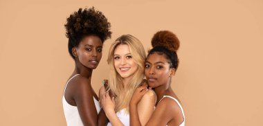 Üç güzel çok ırklı kadın birlikte poz veriyor, kameraya bakıyor. İki afro kız ve bir beyaz sarışının güzel portresi. Cilt bakımı. Çok ırklı dostluk. 