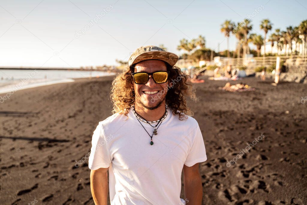 Portrait of a long haired man, hipster, surfer on the beach. Sunset light. Fashionable guy.