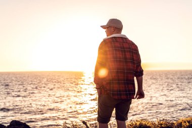 Altın gün batımında denizin kenarında duran bir adam. Yalnız insan batan güneşe bakıyor.. 