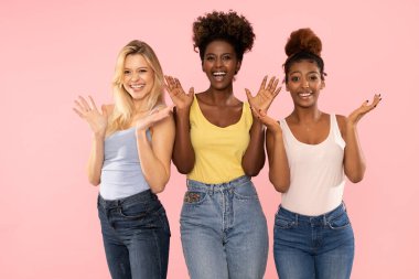 Pembe pastel stüdyo arka planında izole edilmiş üç komik, çok ırklı kızın fotoğrafı. İnsani duygular ve arkadaşlık kavramı