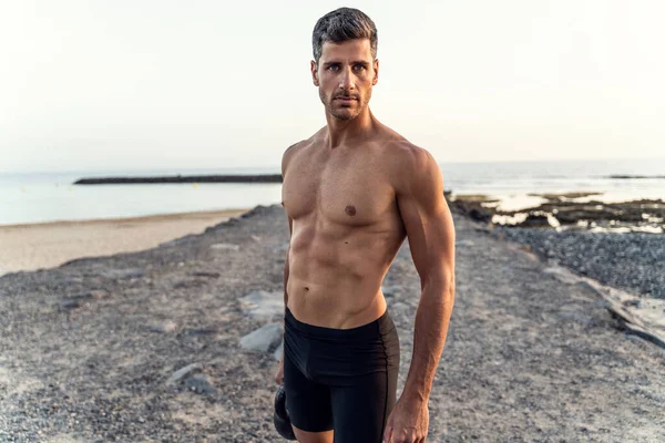 健康英俊的男人在日落时在海滩上锻炼 私人教练训练 完美的身材 — 图库照片