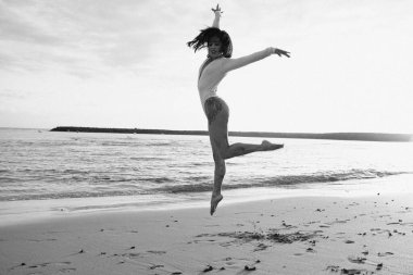 Gün batımında kumsalda dans eden güzel bir kadın. Yaz tatili.