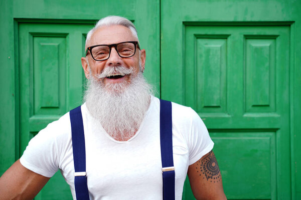 Портрет привлекательного 50-летнего мужчины с белой бородой и усами, улыбающегося в камеру. Фотография на улице