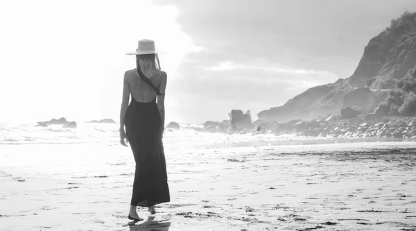 美しいロマンチックな女性は 空のビーチで夕日の間に 夏の帽子をかぶって 海を見て歩く 休暇島のビブ — ストック写真