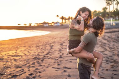 Gün batımında sahilde birlikte eğlenen, gülen güzel genç bir çift. Gerçek insanların duyguları. Sevgi. Yaşam tarzı. Yaz adası titreşimleri.