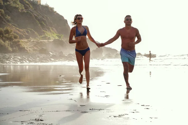 幸せなカップルはビーチで走り ロマンチックな新婚旅行の休暇を楽しんでいます 幸福と真の人々の感情 — ストック写真