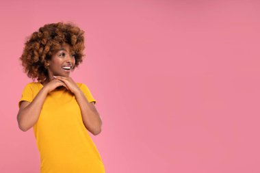 Mutlu güzel afro kız gülümsüyor ve pembe pastel stüdyo arka planında bir fotokopi odasına bakıyor. Renkli fotoğraf. Gerçek insanların duyguları. Satılık..