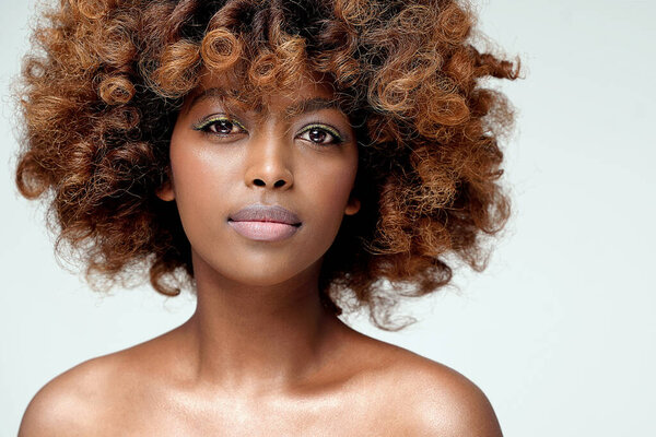 Красота портрет молодой привлекательной афро-женщины с идеальной кожей и нежным гламурным макияжем с желтой подводкой для глаз. Девушка с афро-прической смотрит в камеру. Студийный снимок Много места для копирования.