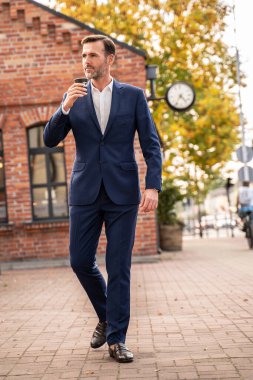 İşten sonra şehirde kağıt kahve fincanıyla yürüyen zarif yakışıklı bir iş adamı. Gerçek insan yaşam tarzı.