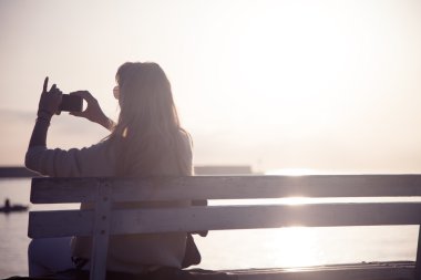 Girl taking photos of sunset.