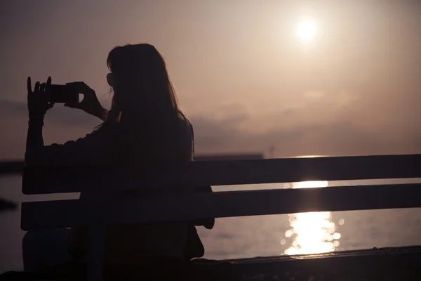 Chica tomando fotos de la puesta del sol . —  Fotos de Stock