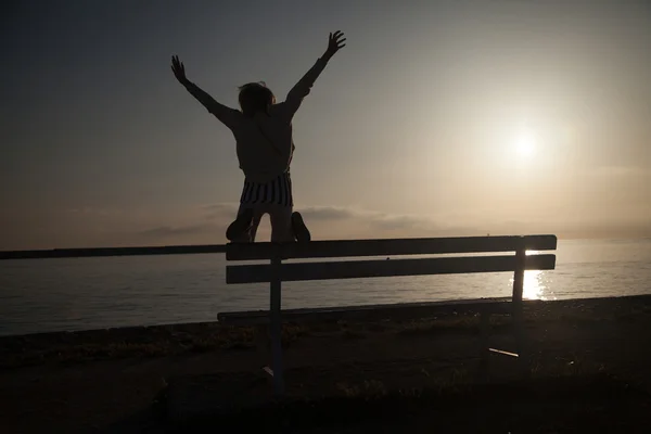 Girl jumping over sunrise. Royalty Free Stock Images