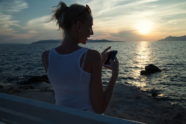 Blondine benutzt Handy im Urlaub. — Stockfoto