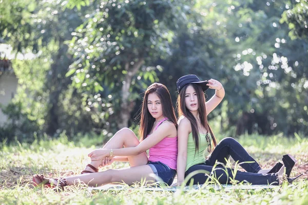 Twee Asia jonge vrouwen zitten op gras — Stockfoto