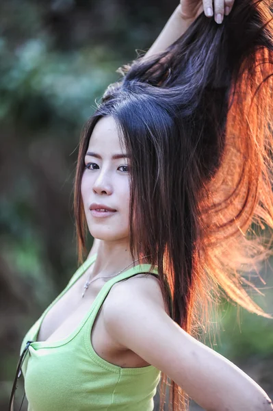 Asiático joven mujer vistiendo verde chaleco, poner su cabello — Foto de Stock