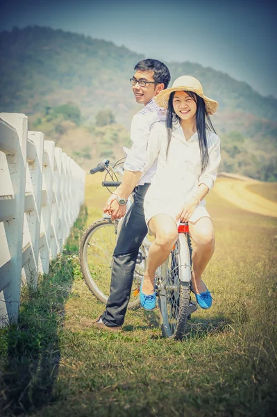Ασίας ζευγάρι με ποδήλατο, βουνό και φόντο — Φωτογραφία Αρχείου
